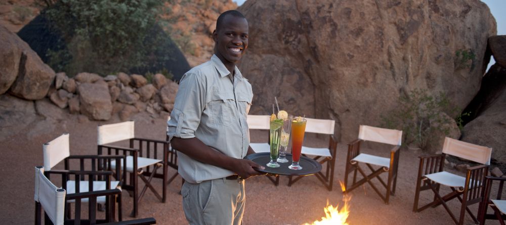 The charming staff serving sundowner cocktails around a campfire at Mowani Mountain Camp, Damaraland, Namibia - Image 9